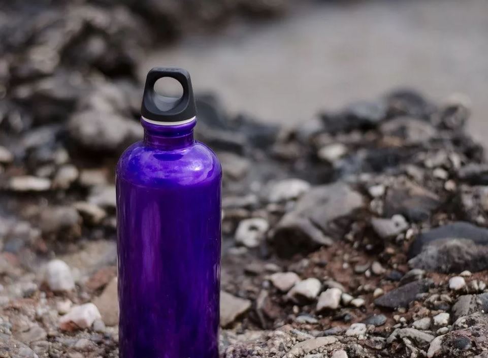 Termiczna butelka na wodę stoi na ziemi