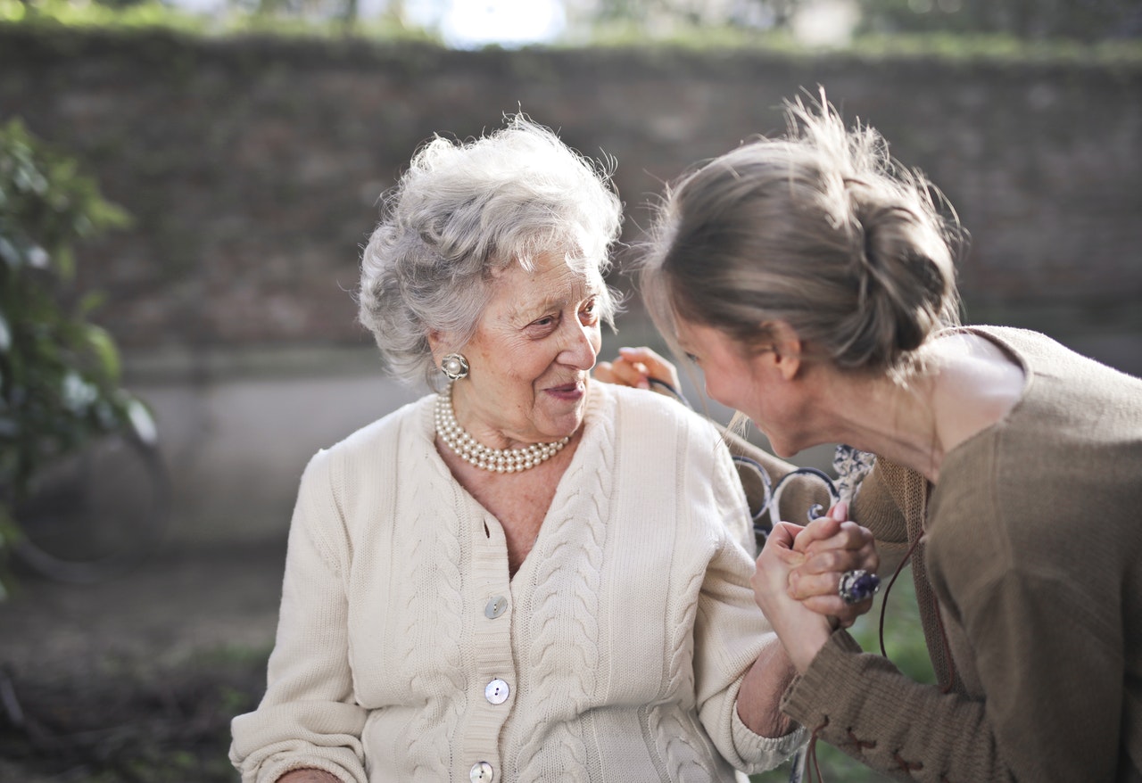 Starsza kobieta chorana serce rozmawia z młodszą kobietą w parku