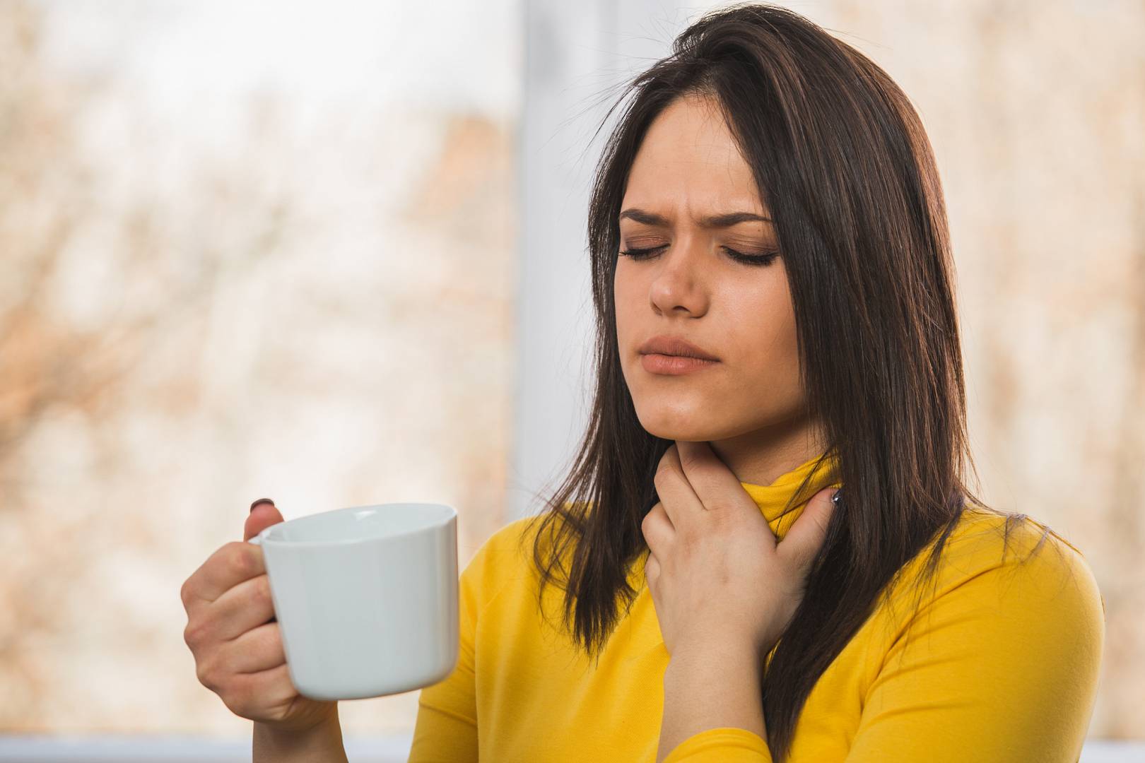 Kobieta leczy swoja infekcję gardła pijąc ciepłą herbate